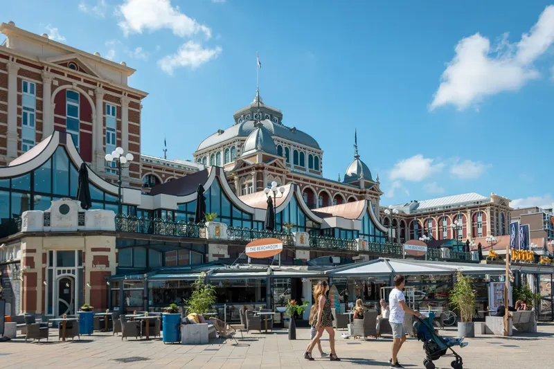 Das historische Kurhaus Scheveningen mit seinem markanten Kuppelbau und der eleganten Strandpromenade. Moderne Gastronomie wie 'The Beachroom' trifft auf prachtvolle Belle-Époque-Architektur am niederländischen Strand. Ein must-see Wahrzeichen mit Restaurants und Terrassen direkt an der Nordsee.
