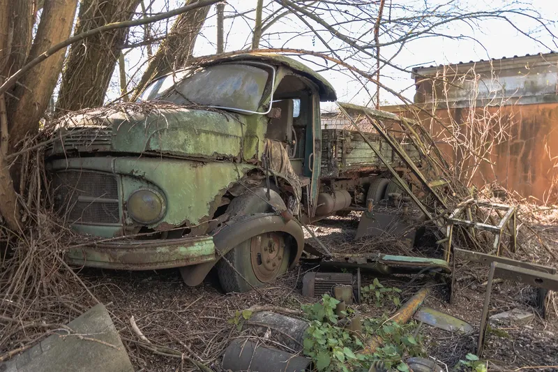 Atmosphärisches Foto eines verlassenen, mintgrünen Mercedes-Benz Oldtimer-LKWs aus den 50er Jahren, umgeben von wilder Vegetation. Lost Places Motiv ideal für Urbex und Automotive-Enthusiasten. Authentische Zeitkapsel der deutschen Automobilgeschichte im natürlichen Verfall.
