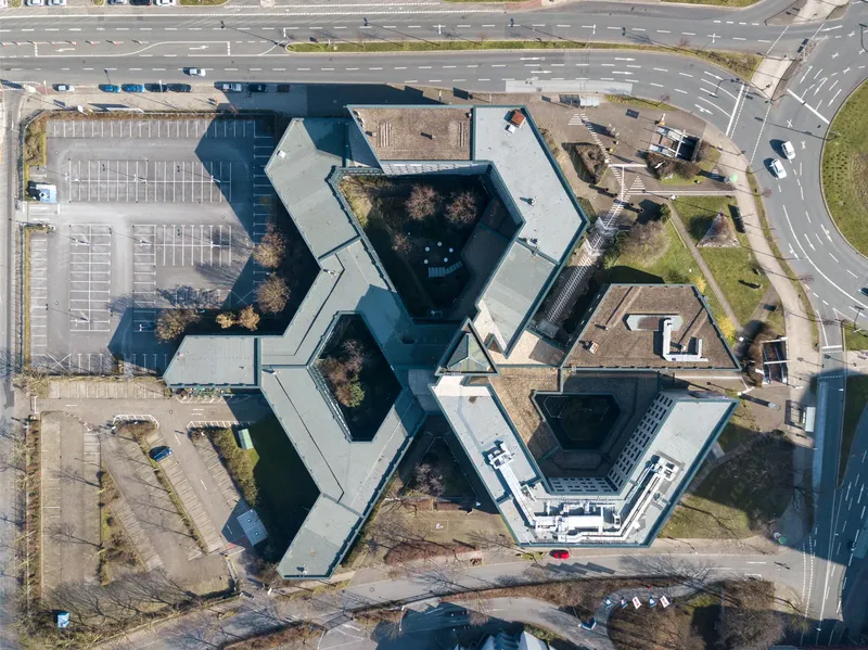 Luftaufnahme der Agentur für Arbeit Essen am Berliner Platz - markante Hexagon-Architektur mit modernem Verwaltungskomplex, Parkplätzen und optimaler Verkehrsanbindung im Herzen von Essen. Zentrale Anlaufstelle für Arbeitssuchende und Arbeitgeber in der Metropole Ruhr.
