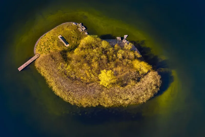 Entdecken Sie die Schönheit des Phoenixsees mit einer beeindruckenden Luftaufnahme einer bewaldeten Insel. Perfekt für Natur- und Fotografie-Enthusiasten.
